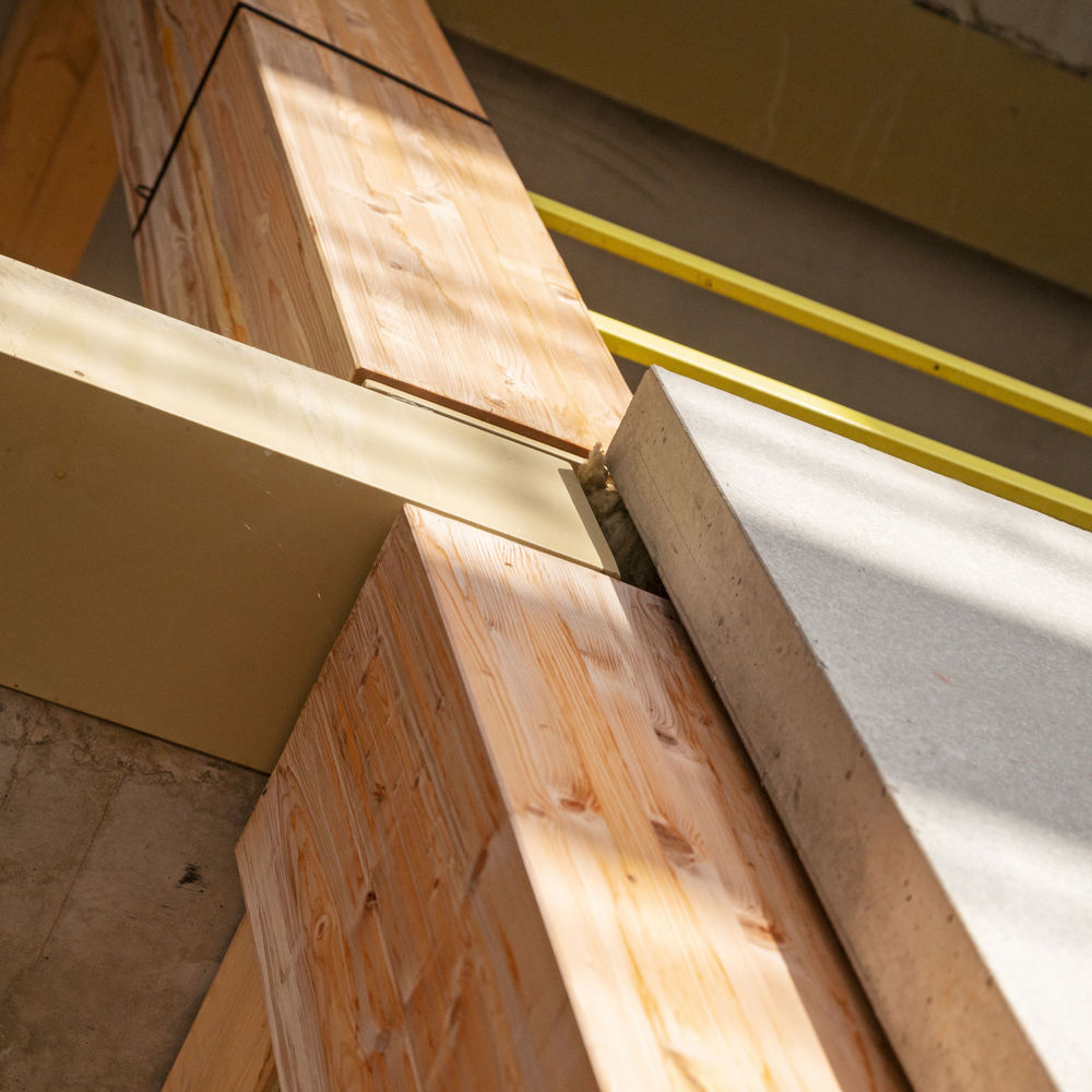Närbild av konstruktion på en byggnad i trä och betong.