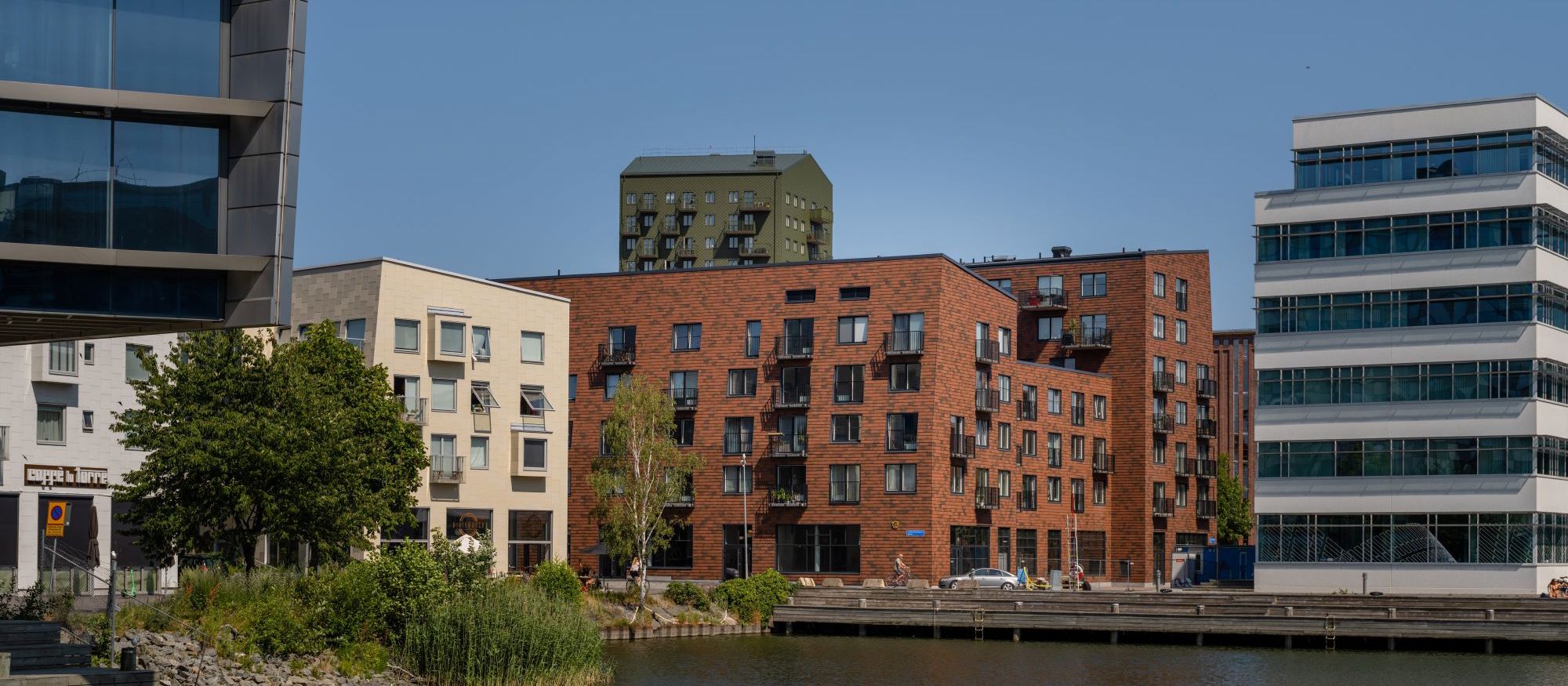 Brf Blanka, Göteborg: bruna flerfamiljshus med omgivande byggnader speglar sig i vatten