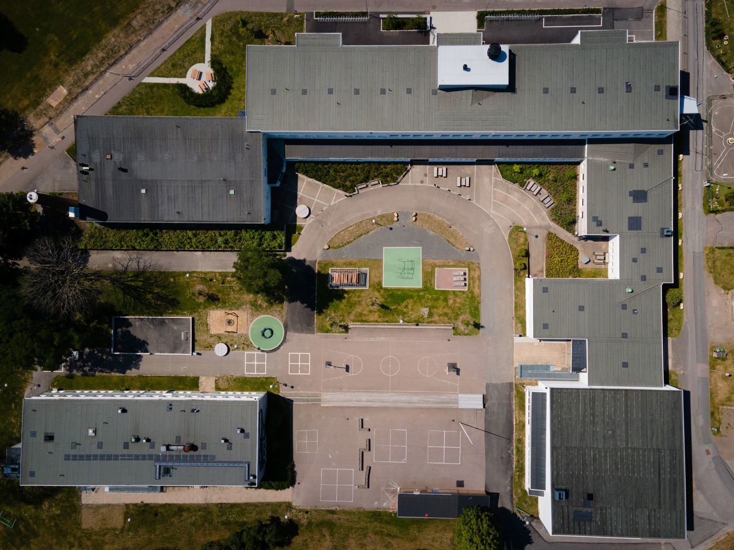 Hålabäcksskolan, Kungsbacka. Drönarbild över flera skolbyggnader runt en solig skolgård.