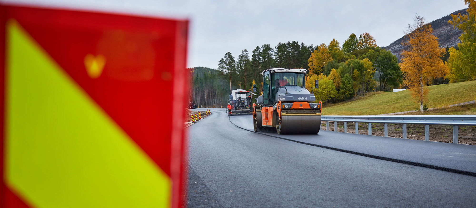 Asfaltsläggning på väg. Skylt i förgrunden