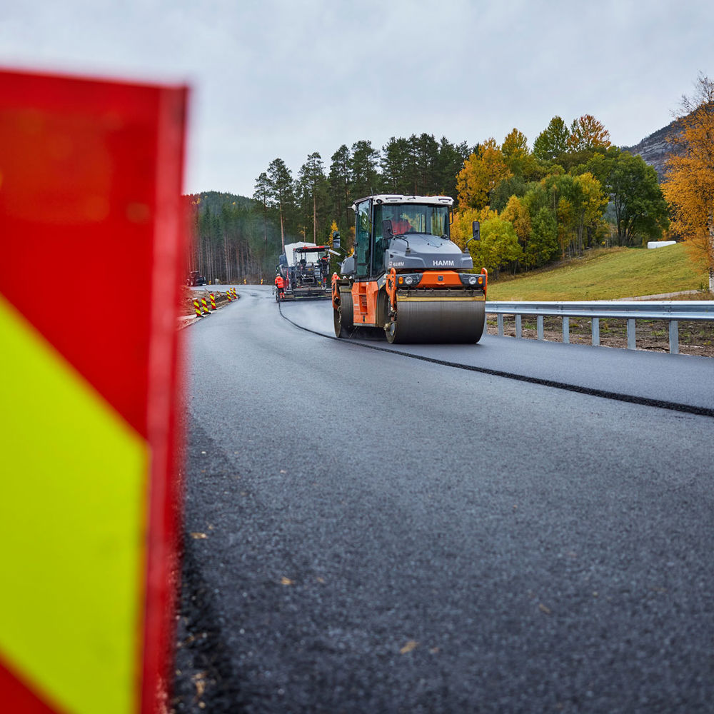 Asfaltsläggning på väg. Skylt i förgrunden