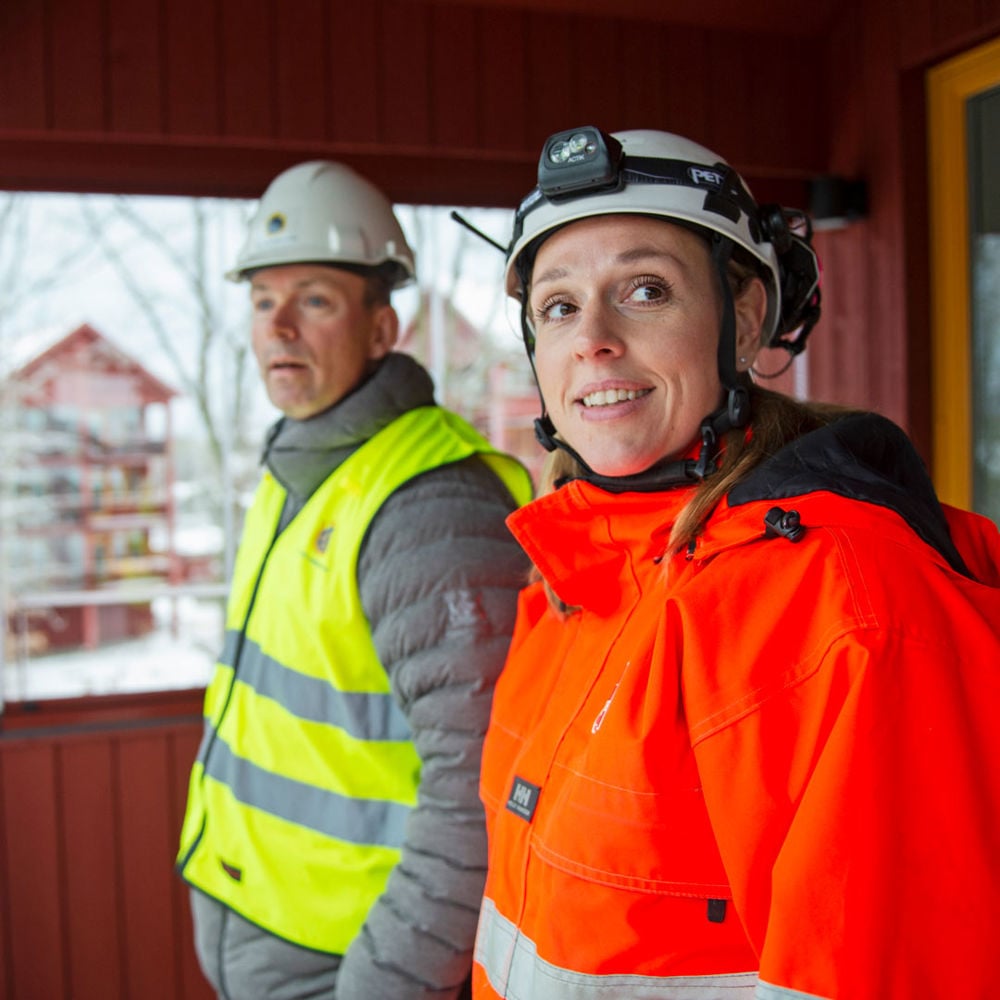 Röda lägenhetshus i trä i vintervitt landskap.