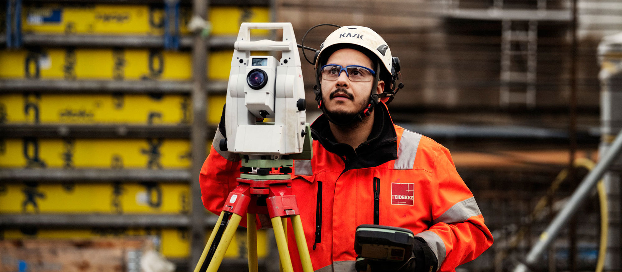 Mättekniker iklädd varselkläder och hjälm tittar i sin mätutrustning