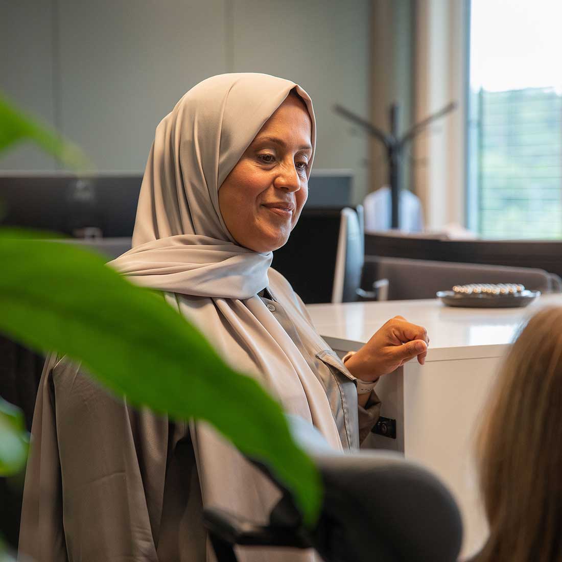 Asma Al-Hassani i samtal med kollega i ett kontorslandskap