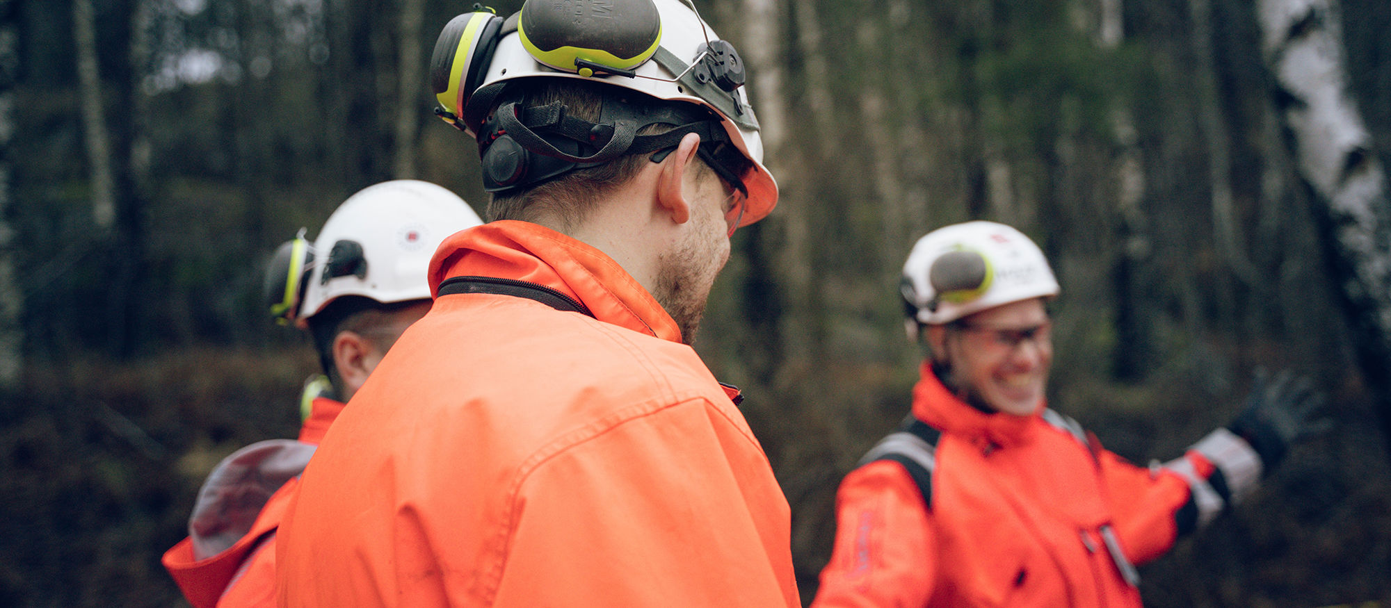 Tre byggarbetare framför en skog